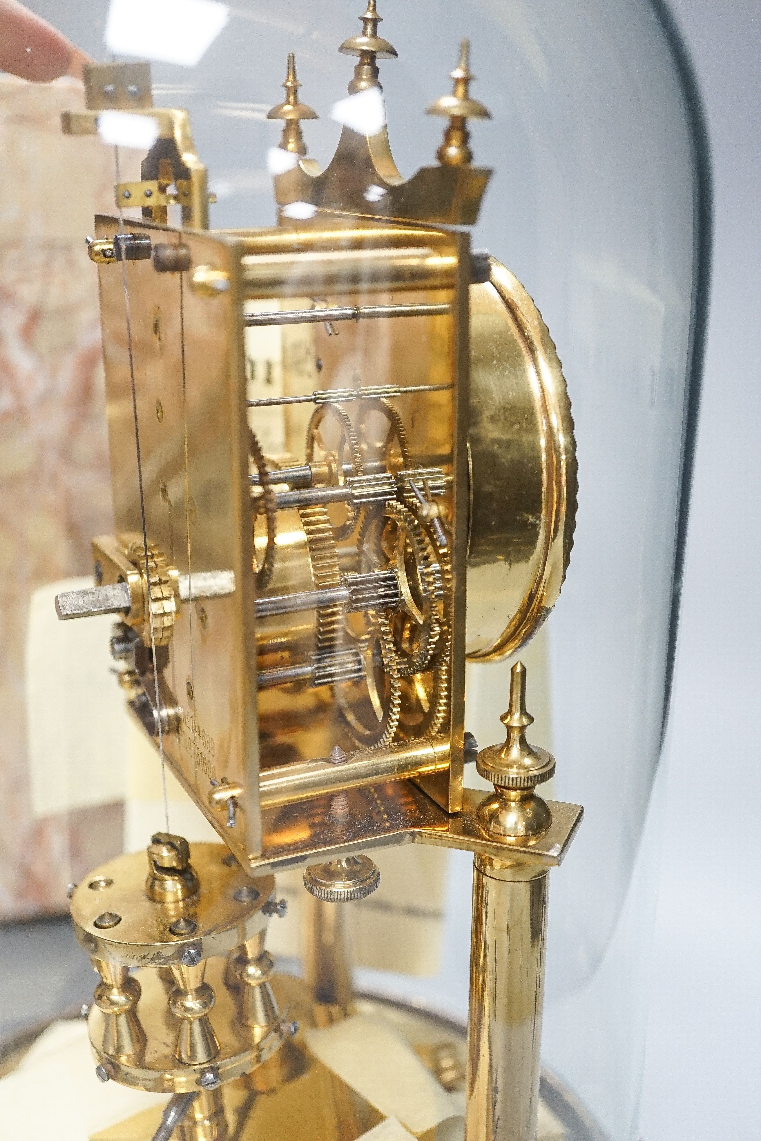 An Art Deco rouge marble mantel timepiece, 45cm wide, quartz movement replacement and a brass anniversary clock under glass dome